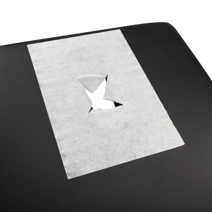 Une housse d’Espace de Respiration Jetable – Pack de 100, blanche avec une fente centrale, est placée sur une table de massage noire.