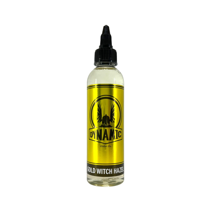 Un flacon en plastique transparent avec embout noir, étiqueté « Encre Viking by Dynamic – Gold Witch Hazel 120 ml » en texte gras sur un fond métallique doré, avec un logo circulaire aux graphiques noirs.
